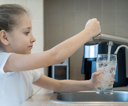 young girl drinking contaminated tap water